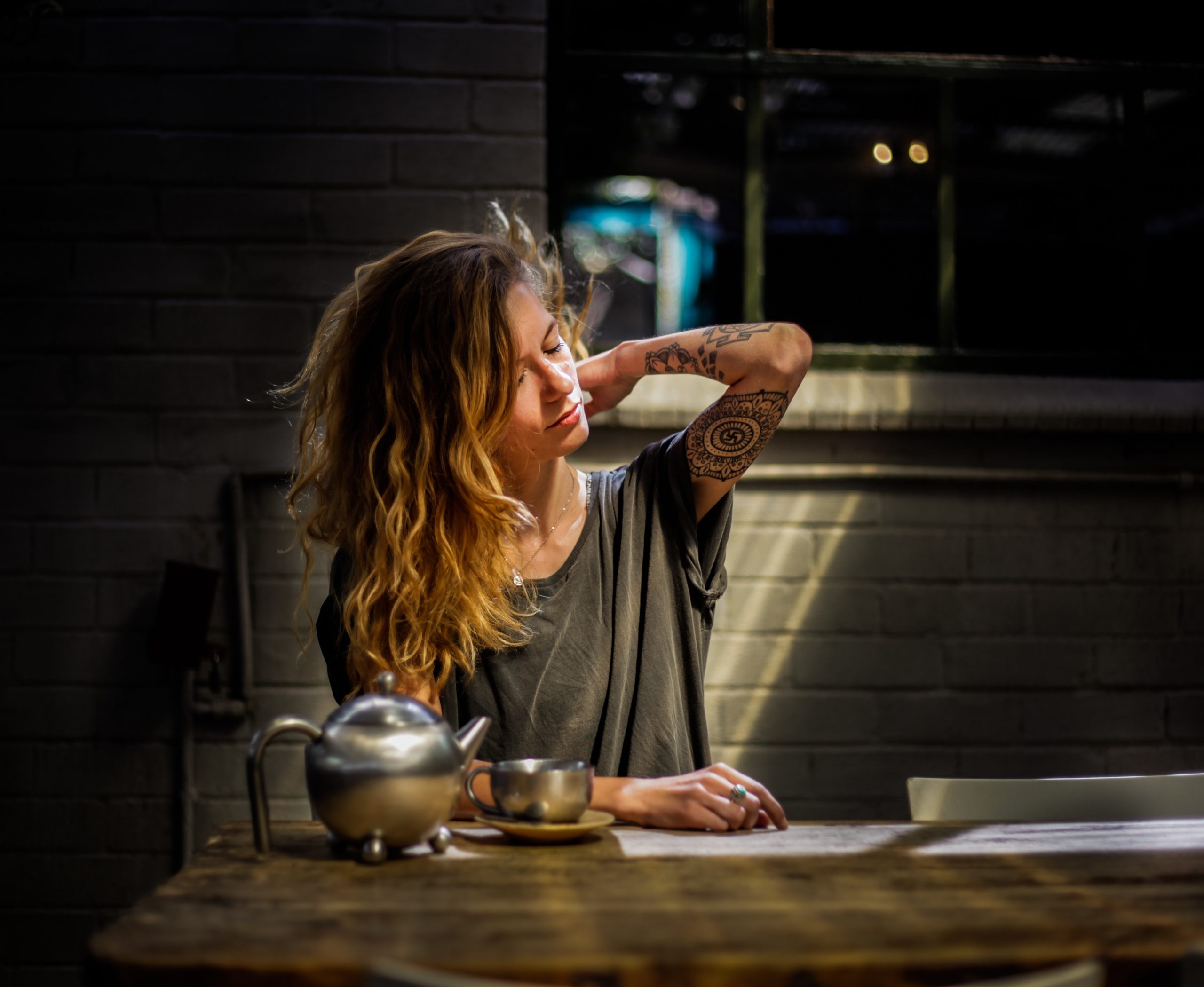 woman sitting at table holding her shoulder