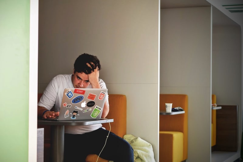 man sitting at laptop holding his head